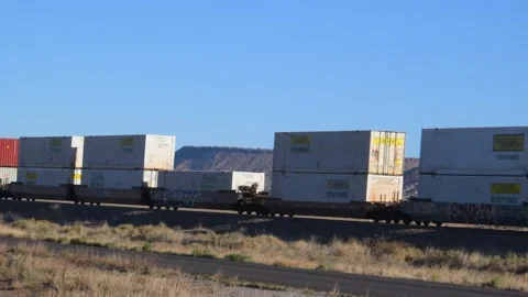 A double-stack freight train traveling through a desert landscape. Stock Footage 334625200