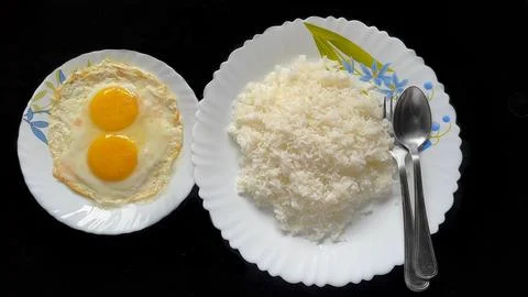 Double sunny side eggs with cooked steam white rice along with fork and spoon Stock Photos