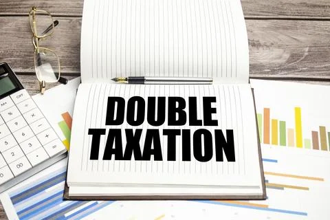 DOUBLE TAXATION text on notepad and calculator with charts Fotos de archivo