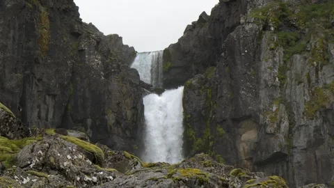 Double tiered waterfall flowing down rugged rocky cliffs in Iceland 4K footage Stock Footage 339909745