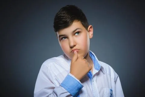 Doubt, expression and people concept - boy thinking over gray background Stock Photos