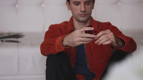 Doubtful man holding ring while sitting on the floor, thinking about proposal Stock-Footage 341017349