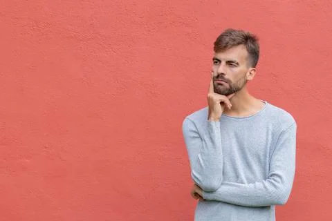 Doubtful man in thinker pose on isolated red wall background Stock Photos