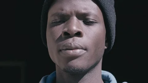 Doubts, thoughts-absorbed face of a young african who squints blinded by the sun Stock Footage 240318756