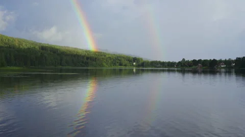 Doubule rainbow in the sky over mountain and lake reflected in water Stock Footage 159093814