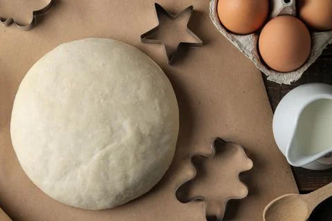 Dough and baking ingredients, biscuit forms and baking tools on a brown woode Foto stock
