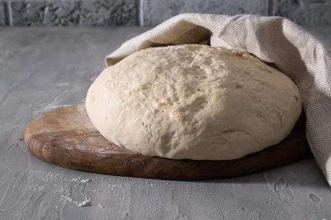 Dough for baking bread or pizza on wooden board. Stock Photos