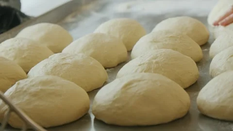 Dough balls are arranged on a tray in a kitchen. They are in the process of Stock Footage 345203200