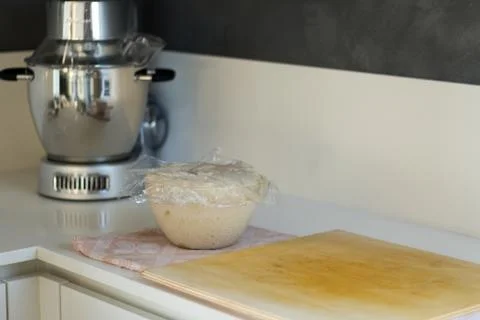 Dough for bread and pizza while rising in the bowl near the mixer Stock Photos