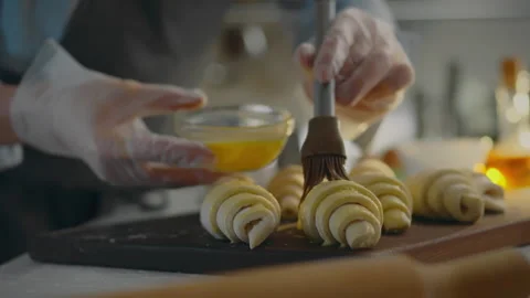 Dough. A chef dressed in an apron brushes the dough with egg in a modern cof Stock Footage 274452743