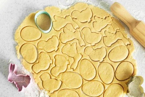 Dough with cookie cutters and rolling pin on kitchen table Stock Photos