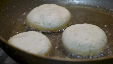 Dough donuts are baking in a boiling oil pan with bubbles, a close-up view Vidéo 264782609