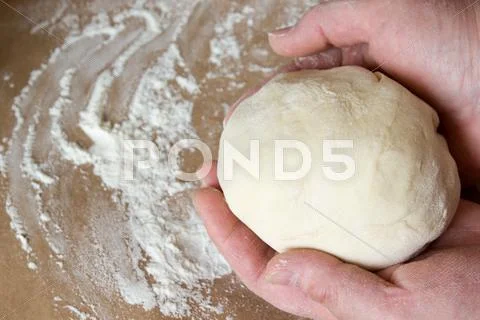 The Dough In His Hands On The Table With Flour.