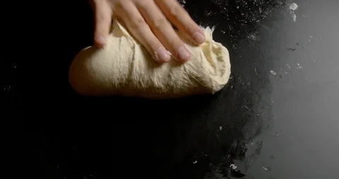 Dough kneading by hand on black table Stock-Footage 128753424