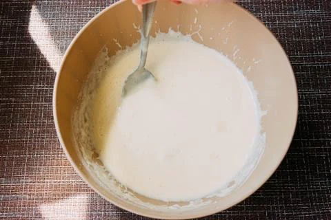 Dough for making pancakes or omelet in a bowl with a whisk in the kitchen.hom Stock Photos