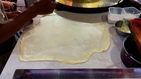 The dough of martabak shell is stretched and twisted by hand on the flat Stock Footage 279798762