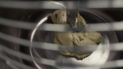 Dough mixture being kneaded in a stainless steel bowl by a metal mixer Stock Footage 331755435