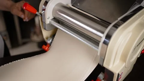 The dough passes through a pasta machine. Slow motion Stock Footage 256148068