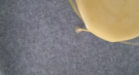 The dough is poured onto parchment paper on a baking sheet. Video stock 220105440