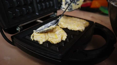 Dough pours from spoons on a waffle iron making homemade waffles Stock Footage 202290472