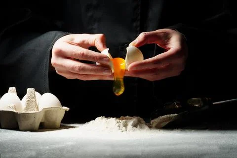 Dough preparation process on a dark background. The woman breaks the egg and 스톡 사진