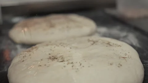 Dough preparation process with seasoned bread dough being shaped and placed on a Stock Footage 331755472