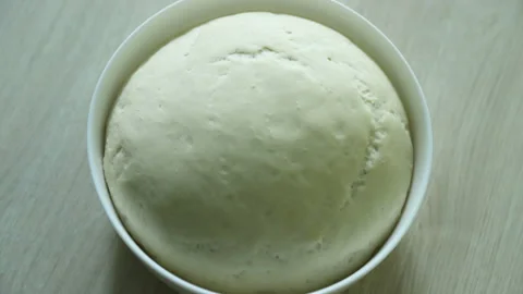 Dough rising, time lapse. Yeast dough rising on white bowl on wooden table. Stock Footage 114349932