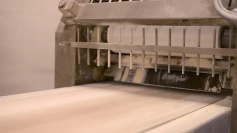 Dough rolled flat deposited onto a conveyor belt in a bread factory Stock Footage 107049321