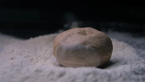 Dough for a small round bread falls on a heap of flour Stock Footage 139117376
