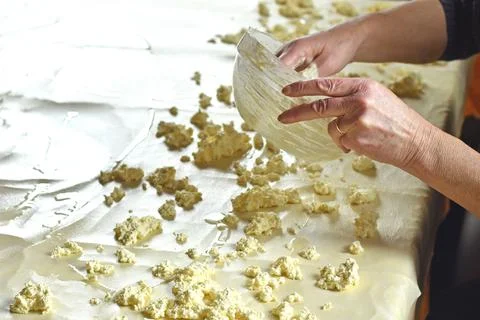 Dough for strudel, stretched on a kitchen table and adding curd cheese on it Stock Photos