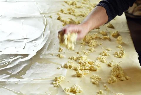 Dough for strudel, stretched on a kitchen table and adding curd cheese on it Stock Photos