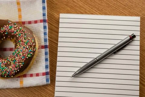 Doughnut and notepad with pen Stock Photos