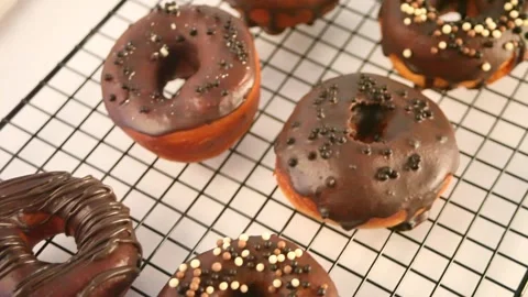Doughnut on the baking rack glazed with chocolate cream or icing. Stock Footage 145121874