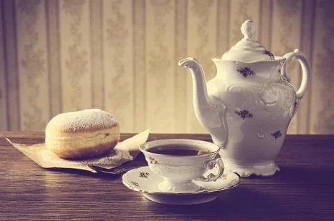 Doughnut with cup of tea with old-fashioned wallpaper Stock Photos