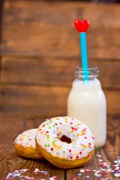Doughnuts with mini bottle of milk and straw with heart. Focus on doughnuts Stock Photos