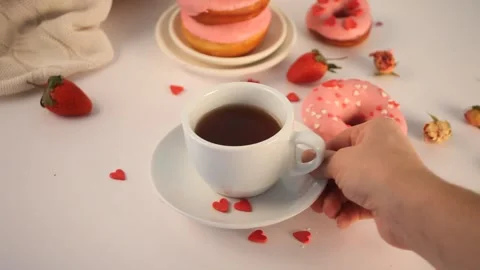 Doughnuts on the plate. Valentine's Day concept. Woman hand put a cup of tea on Stock Footage 145122124