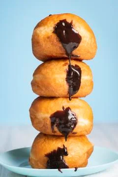 Doughnuts stack on a blue plate. Chocolate Berliner donuts tower Stock Photos