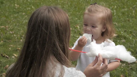 Doughter with mom in the park having fun and sharing cotton candy. Stock Footage 99487702