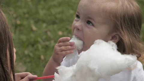 Doughter with mom in the park having fun and sharing cotton candy. 库存影片 99487750