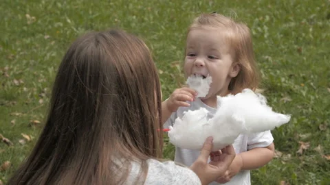 Doughter with mom in the park having fun and sharing cotton candy. Stock Footage 99487787