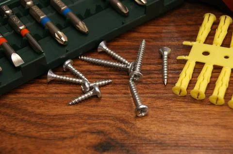 Dowels, screws, bit set. Tools and fasteners on a wooden surface Stock Photos