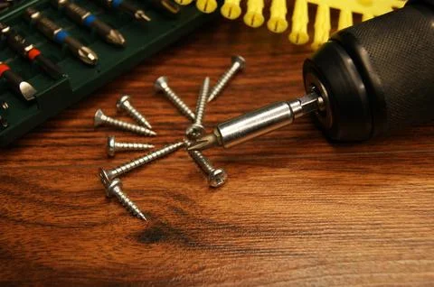 Dowels, screws, screwdriver, bit set. Fitter's workplace. Stock Photos