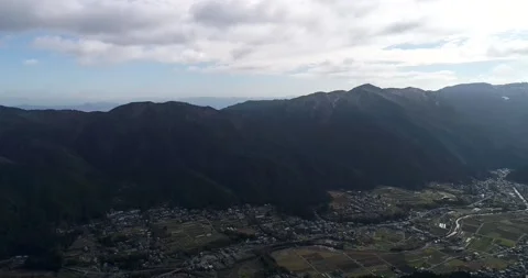 Down from cloudy sky and mountain range to local valley of Ohara village, Japan. Stock Footage 135874897