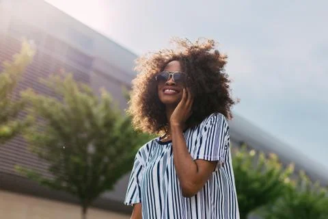 Down view of the beautiful smiling afro-american girl talking via the mobile Stock Photos