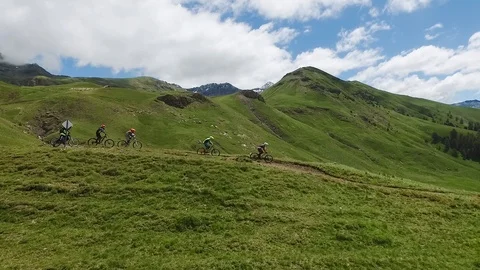 Downhill biking aerial view. Group of mountain bikers tracking on green hilltop. Stock Footage