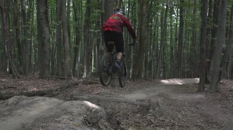 Downhill mountain biker jumping over a kicker Stock Footage 53869958