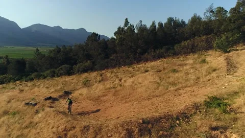 Downhill mountain biker rides banked corners on sandy meadow trail 動画素材 330861664