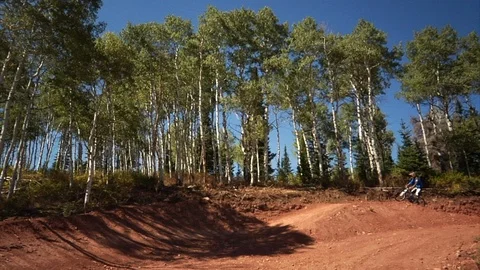 Downhill mountain biker rides fast around dirt berm trail. Video stock 106791753