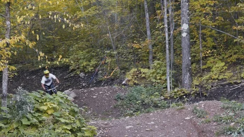 Downhill Mountain biker rides off jump Stock Footage 88687368