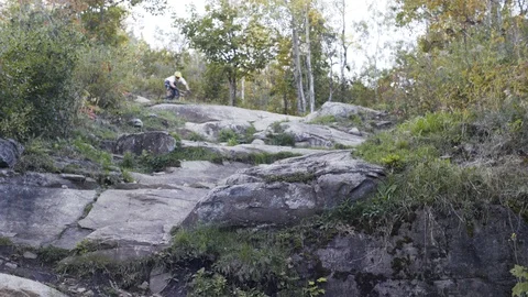 Downhill Mountain biker rides through rocks Stock Footage 88687537